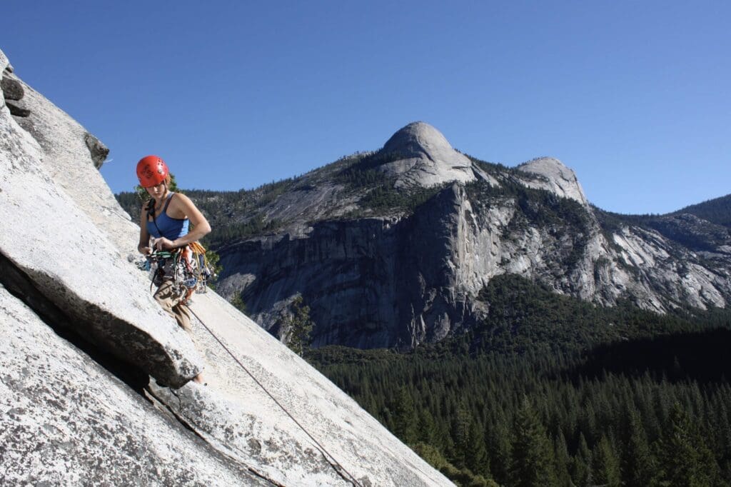 Kyle Khalil paused while climbing to inspect a rack of cams as she leads a pitch on one of Yosemite's granite walls. 