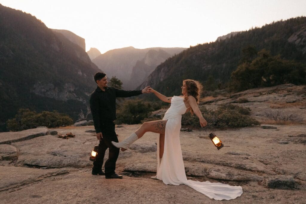A groom and bride dance on exposed granite atop Yosemite's iconic tunnel view bathed in the light of dawn. 